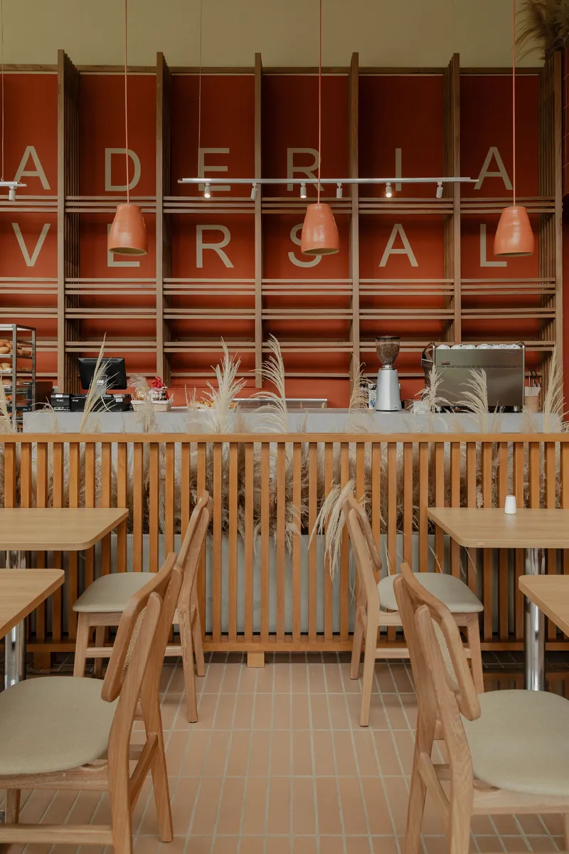 Vitrina curva de exhibición con panes y pasteles frente a un muro de madera con el rótulo Panadería Universal