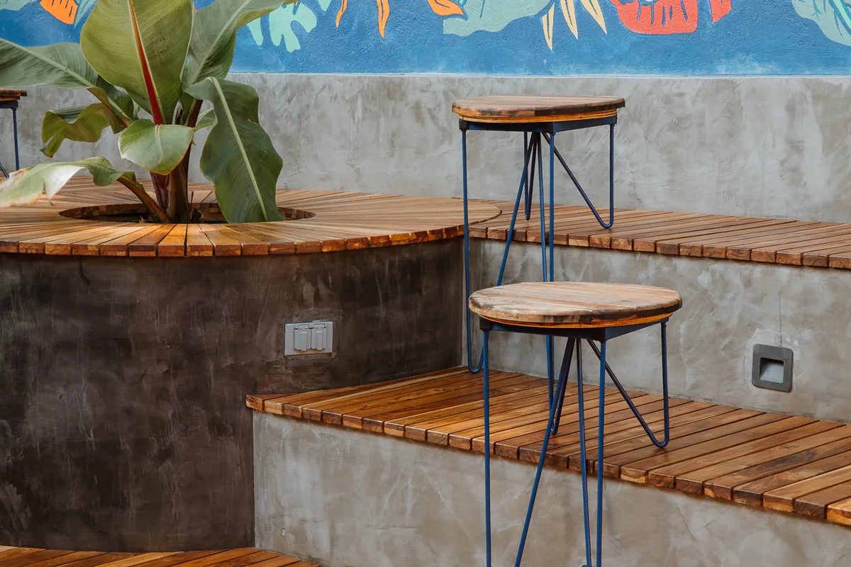 Detalle del mural tropical con hojas y frutos de café pintado sobre el muro azul del patio