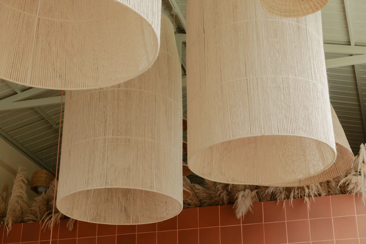 Muro de madera ranurada con el rótulo Panadería Universal y lámparas de fleco tejidas colgando