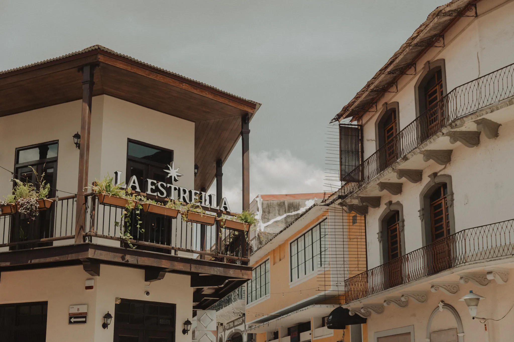 Fachada del edificio colonial de Barra la estrella en el Casco Antiguo de Panamá, con balcón de madera, plantas colgantes y el letrero La Estrella bajo un cielo nublado