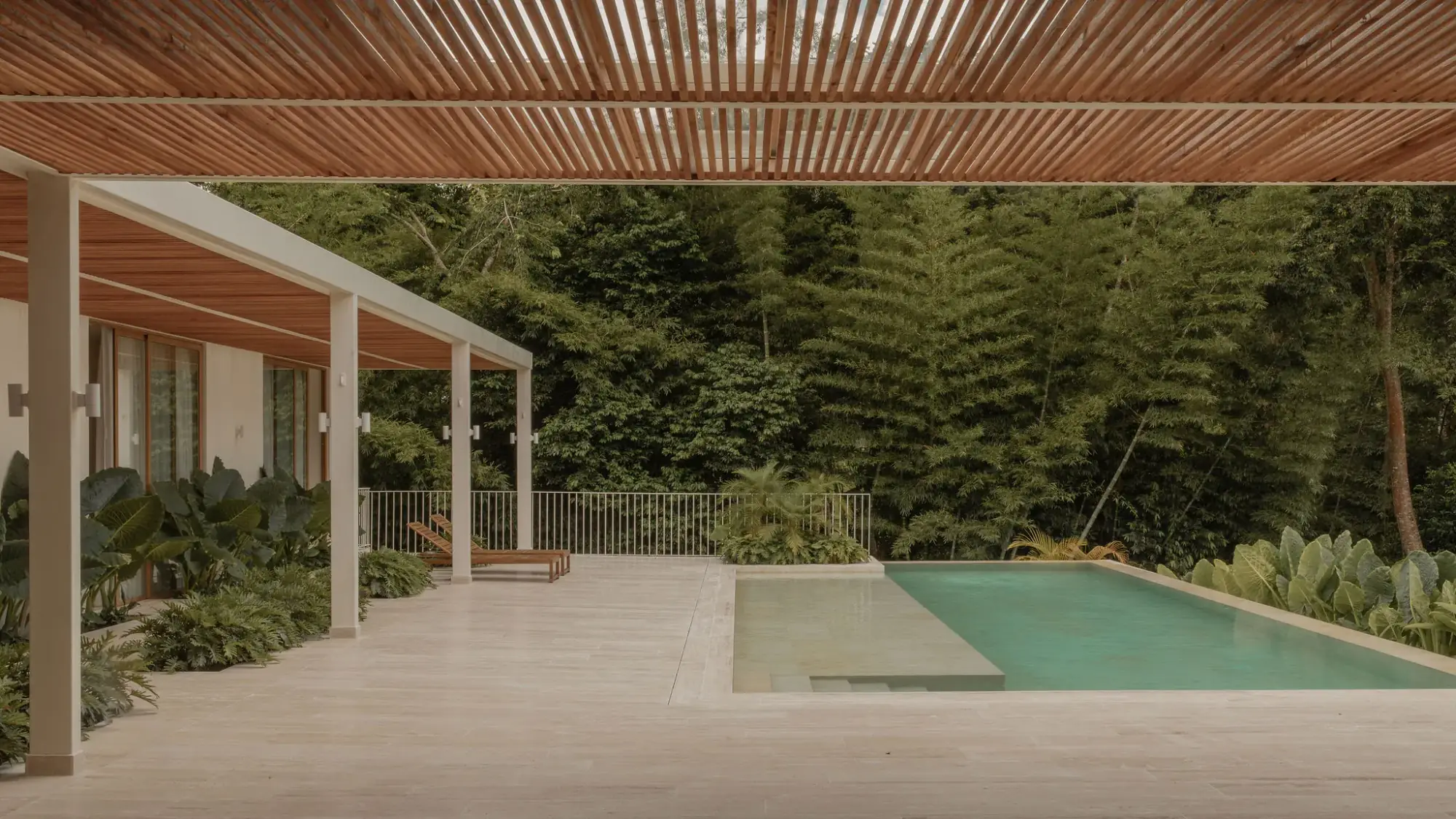 Casa N vista desde la piscina, con techo de teja de barro, terraza cubierta abierta a la cocina y comedor