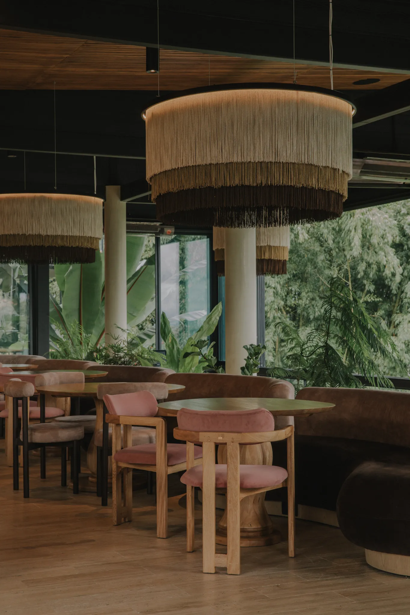 Salón de Mirum con lámparas de fleco tejidas colgando entre columnas blancas y vista al bosque circundante
