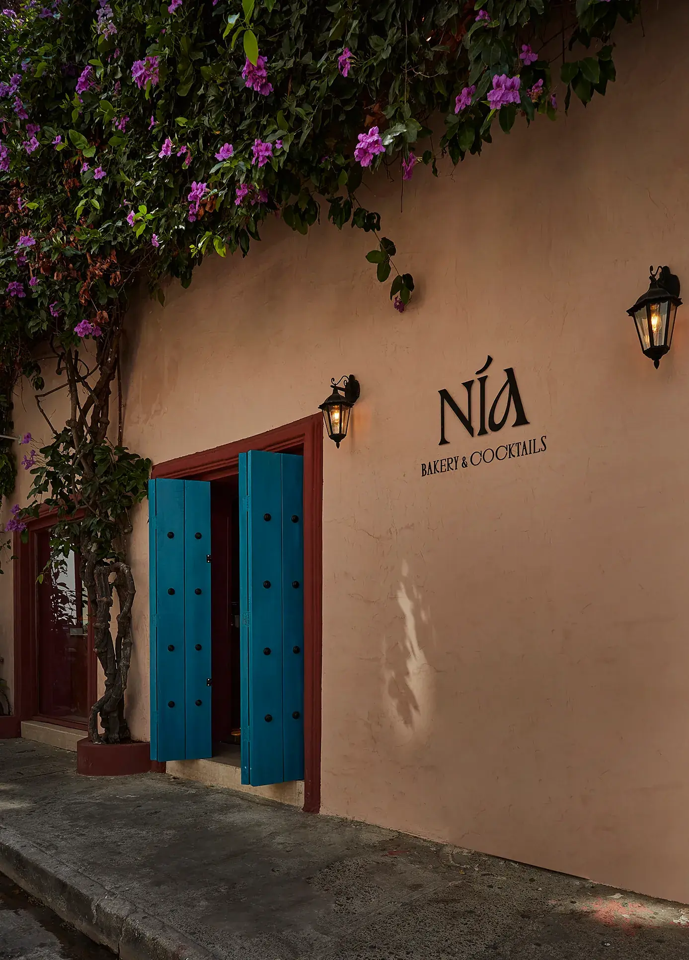 Fachada de Nia Bakery en Cartagena, con arcos de piedra, plantas colgantes y el letrero Nía sobre la entrada
