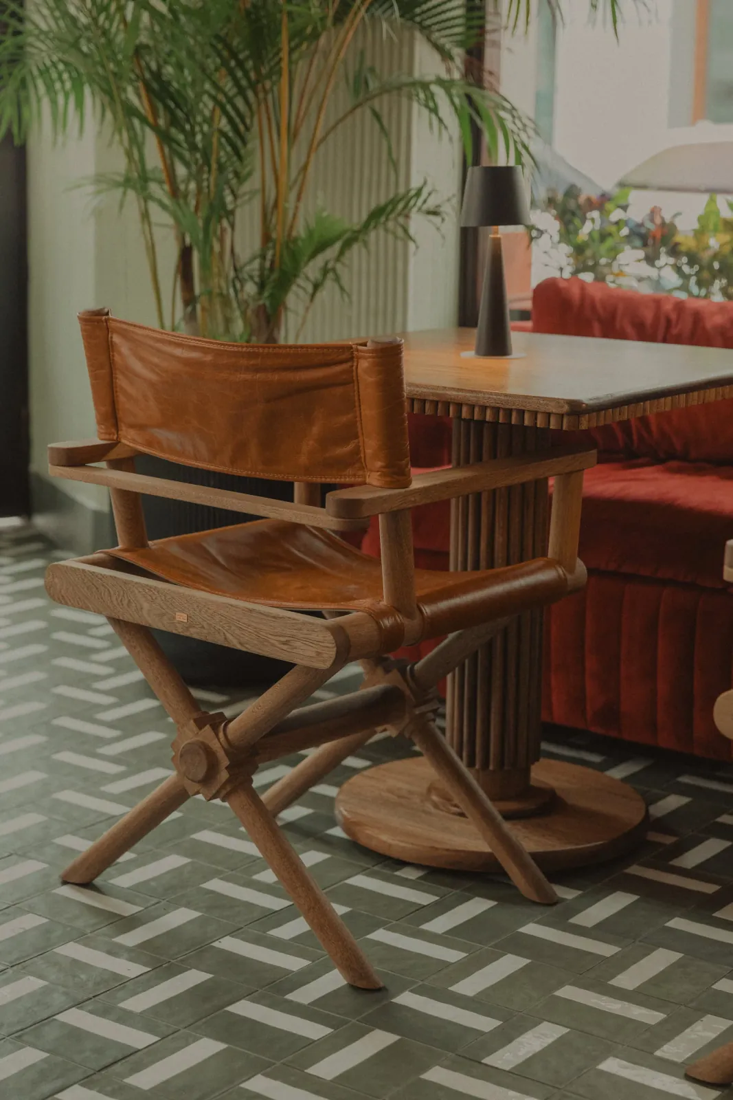 Silla plegable en cuero y madera de diseño personalizado junto a una mesa a medida con base torneada